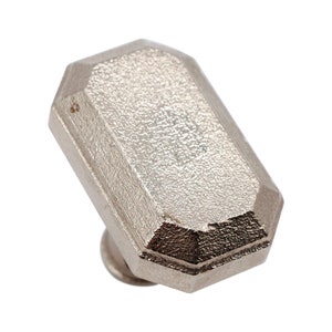 May include: A silver, faceted, rectangular cabinet knob with a textured surface.