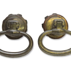 May include: Two antique brass oval ring cabinet pulls with a decorative, ornate, round top.