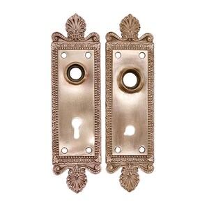 Puede incluir: Dos placas de puerta de latón antiguo con diseños ornamentados y agujeros para llaves. Las placas son rectangulares con un borde decorativo y un diseño floral en la parte superior.