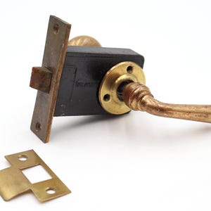 以下が含まれることがあります： 黒い本体、真鍮製のハンドル、ストライクプレートを備えたアンティークのドアロックセット。 ハンドルは湾曲しており、真鍮製のノブが含まれています。 ロックはヴィンテージである可能性が高く、摩耗の兆候が見られます。