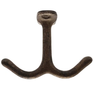 May include: A double-pronged, cast iron hook with a dark brown finish. The hook is designed for hanging items on a wall.