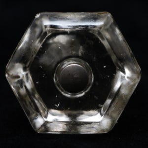 Peut inclure: Un bouchon de bouteille hexagonal en verre transparent avec un capuchon métallique au centre.