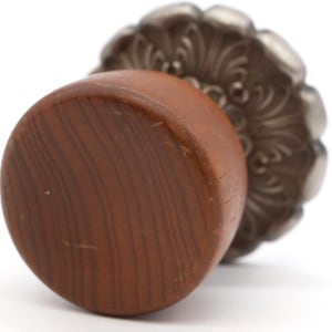 May include: A wooden knob with a silver, ornate, floral design. The knob is brown and has a smooth, polished finish.
