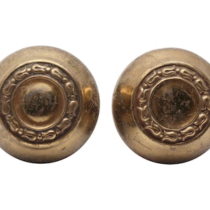 May include: Two antique brass door knobs with a decorative floral design.