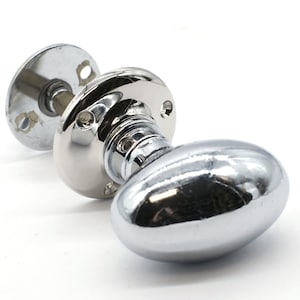 以下が含まれることがあります： 丸いベースと取り付け用のネジが付いたクロム製の楕円形のドアノブです。