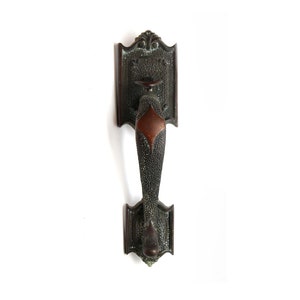 May include: Antique bronze door handle with a diamond-shaped insert. The handle has a decorative design and is attached to a square plate.