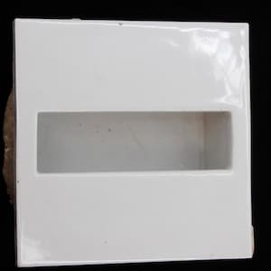 May include: White ceramic wall mounted soap dish with a rectangular opening.