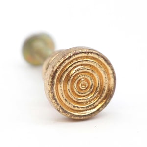 Peut inclure: Un bouchon de bouteille en métal doré avec un motif circulaire à anneaux concentriques.