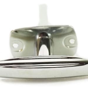 Może przedstawiać: Błyszcząca, chromowana klamka do drzwi z prostokątną podstawą i zakrzywionym, poziomym uchwytem. Podstawa ma dwa okrągłe otwory. Uchwyt został zaprojektowany z myślą o łatwym chwytaniu i otwieraniu drzwi.