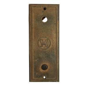 May include: A vintage brass elevator button plate with the word "Staley" embossed in a circle. The plate has two round buttons, one with a black centre and the other with a hole.