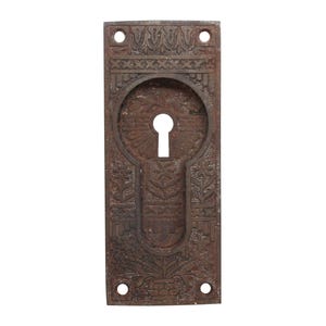 Peut inclure: Un cache-trou de serrure en fonte vintage, orné et décoratif. Le cache est brun et possède un trou de serrure au centre.