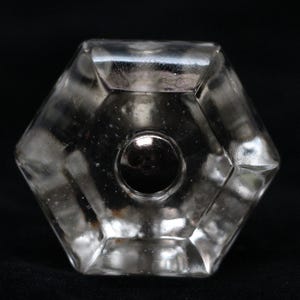 May include: A clear glass hexagonal knob with a silver metal centre. The knob has a faceted design and is ideal for adding a touch of vintage charm to any cabinet or drawer.