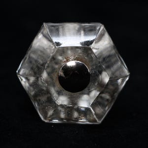 Könnte beinhalten: Ein durchsichtiger, sechseckiger Türknauf aus Glas mit einem silbernen Metallkern.