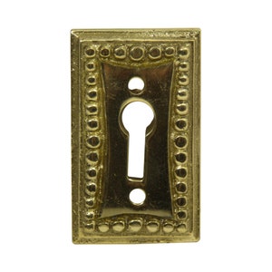 May include: A brass keyhole cover with a decorative beaded border.