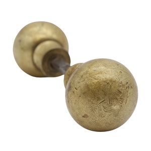 May include: A pair of antique brass door knobs with a worn finish. The knobs are round and have a simple design.