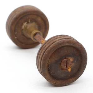 May include: A pair of wooden wheels connected by a metal rod. The wheels are brown and have a slightly worn finish. The rod has a metal screw in the center.