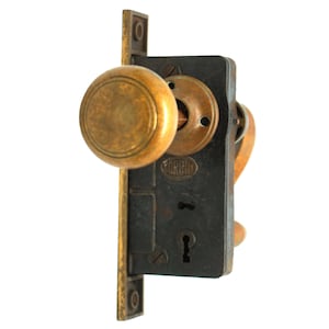 May include: A vintage brass door knob and lock set with a black metal plate and a keyhole. The knob has a round, slightly raised design. The lock plate has the word "UNION" embossed on it.