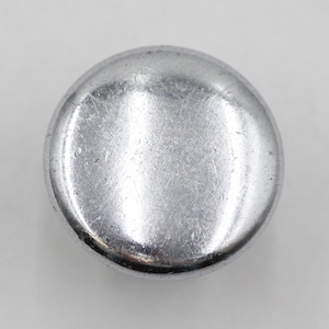 May include: A silver-coloured metal button with a smooth, slightly rounded surface.