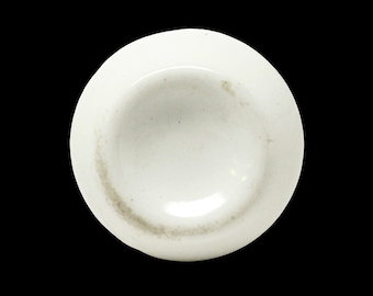 May include: White ceramic plate with a slightly raised center. The plate has a subtle, uneven texture and a faint gray ring around the edge.