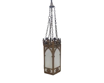 May include: A vintage, ornate, gold-toned metal chandelier with a white glass shade. The chandelier has a gothic design with intricate details and hangs from a chain.