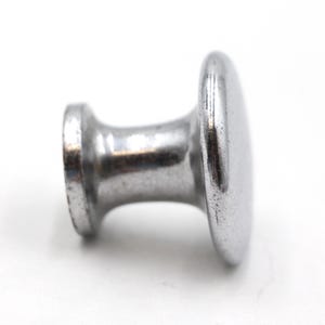 May include: A silver metal knob with a round top and a cylindrical base.