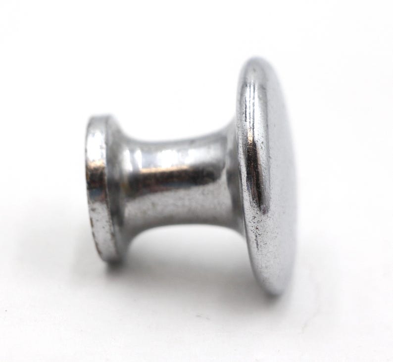 May include: A silver metal knob with a round top and a cylindrical base.