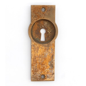 Puede incluir: Una tapa de mirilla de latón vintage con una abertura de mirilla redondeada. La tapa tiene una pátina desgastada y envejecida.