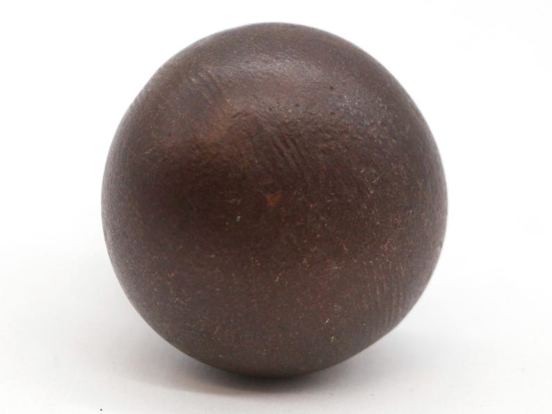 Puede incluir: Una bola redonda de arcilla de color marr&oacute;n oscuro y lisa.