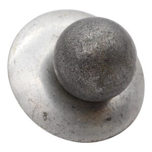 May include: A silver metal ball bearing sits on a larger, flat, silver metal disc.