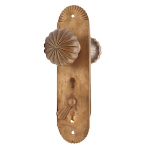 Può includere: Set di maniglie per porte in ottone antico con placca lunga. Il set presenta due pomelli rotondi e scanalati e una serratura. La placca ha dettagli decorativi a forma di raggiera e floreali. L'hardware è di colore ottone caldo.