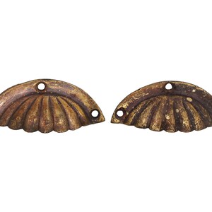 Op de afbeelding: Twee antieke messing kastgrepen in de vorm van een schelp. Elke greep heeft drie gaten voor bevestiging.
