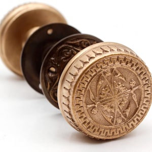 May include: A selection of antique brass door knobs, displayed in a row. The knobs are in different stages of assembly, revealing their detailed designs and aged patina. The knobs have a detailed, circular design.