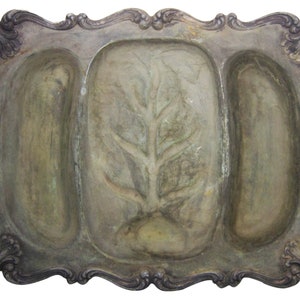 May include: A silver serving tray with three compartments. The center compartment has a raised design of a leafy branch. The tray has a decorative, ornate border.