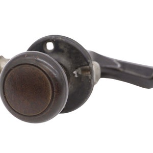 Op de afbeelding: Een donkerbruine houten deurknop met een metalen achterplaat en een lange, donkerbruine houten hendel.