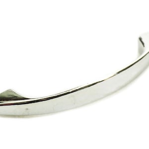 May include: A shiny, silver-colored cabinet pull handle. The handle has a curved design with pointed ends. The hardware is made of metal and is designed to be mounted on a cabinet door or drawer. The handle is shown against a white background.