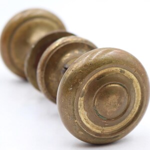 Peut inclure: Gros plan sur un ensemble de boutons de porte anciens en laiton. Les boutons sont de couleur or vieilli et chaleureux avec un motif circulaire. Les boutons sont disposés en rangée, le plus proche étant mis au point. Le fond est blanc.