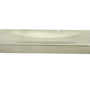 Puede incluir: Un tirador de puerta rectangular de níquel cepillado con una parte superior ligeramente curvada.