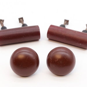 Può includere: Set di quattro pomelli per armadi in plastica marrone. Due sono rotondi e due sono cilindrici.