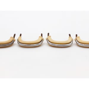 May include: Four vintage cabinet handles. Each handle has a curved, light tan grip with a silver-coloured metal base. The mounting posts are brown. The handles are arranged horizontally against a white background.