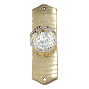 May include: A vintage door knob with a clear, faceted glass knob and a rectangular brass backplate. The backplate has a slightly aged appearance with two screw holes at the top and bottom.