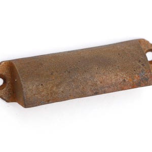Könnte beinhalten: Ein rustikaler, brauner Metall-Schubladenzug mit leicht abgerundeter Form und abgerundeten Kanten. Der Zug hat eine abgenutzte Oberfläche, die ihm einen Vintage-Look verleiht.