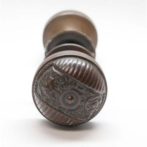 May include: A pair of antique door knobs with a detailed, ornate design. The knobs are made of a dark metal and have a textured surface.