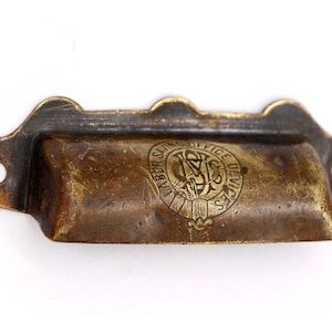 Può includere: Tiramaniglia per cassetto in ottone con un design circolare in rilievo che recita "Labor Saving Office Devices".