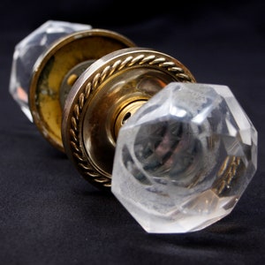 May include: A vintage door knob with a brass base and two clear glass crystal knobs. The glass knobs have a faceted design.
