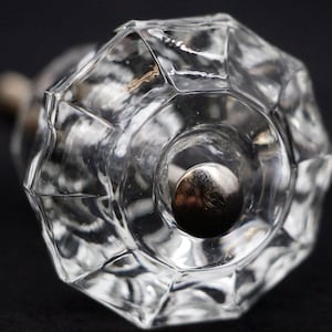 Può includere: Un pomello per armadio in vetro trasparente con un design sfaccettato e una base in metallo argentato.