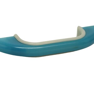 May include: A blue plastic handle with a white trim. The handle is curved and has a smooth surface.