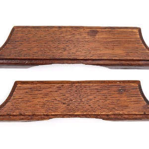 May include: Two rectangular wooden drawer pulls with a natural brown wood grain finish. Each handle features a slightly curved top edge and flared, angled sides, showcasing a distinct textured surface with visible dark brown wood grain patterns.