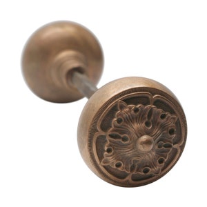 May include: A vintage brass door knob with a decorative floral design. The knob is round and has a smooth, polished finish.