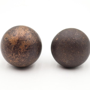 May include: Two spherical decorative objects with a dark brown, textured finish. The spheres have a mottled appearance with hints of copper and bronze tones, set against a white background.