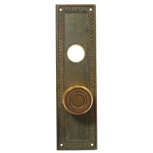 May include: A brass door plate with an ornate design and a round knob. The plate has a keyhole and a decorative border.